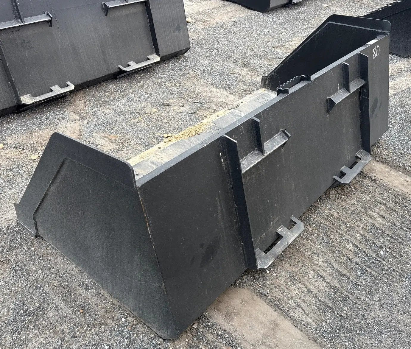 Skid steer snow bucket, black, 80-inch high-capacity universal attachment; several buckets visible